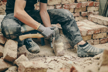 A young man cleans bricks with an axe.