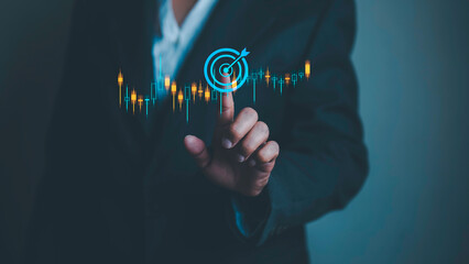Businesswoman reaches out to touch success goal symbol regarding stock investment and stock market fluctuation candlestick chart. Investment concepts in the digital financial market.