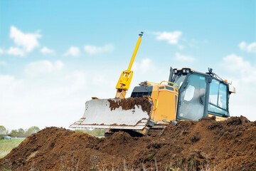 Construction Equipment Digging Earth in Open Field Under Clear Sky © Iryna