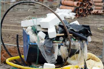 Construction Site Waste Heap Surrounded by Tools, Debris, and Materials on Overcast Day