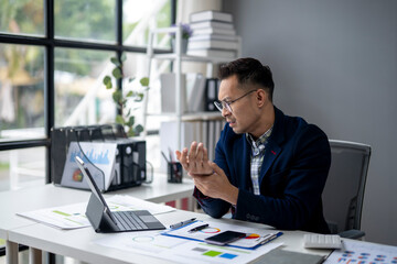 A man in a suit is sitting at a desk with a laptop and a tablet