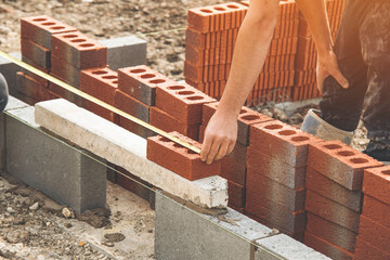 Construction Worker Laying Red Bricks on Foundation During Daylight in a Building Project