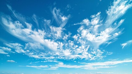 Wispy clouds spread across clear blue sky at midday