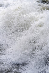 Sea foam, splashes and spray of a large wave on the coast.