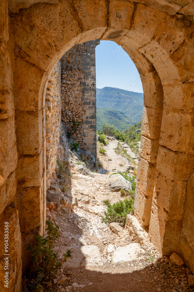 Wall mural Vertical photo of one of the entrance gates to the medieval Chirel Castle in Cortes de Pallas, Valencia, Spain, on a hill with intense natural light