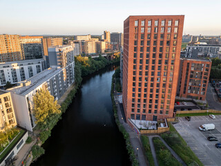 Aerial view of modern apartment buildings with a river Irwell and Manchester city skyline in the background.