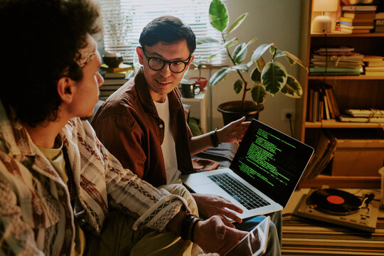 Student holding laptop processing data and looking at his friend with excitement on face - Powered by Adobe