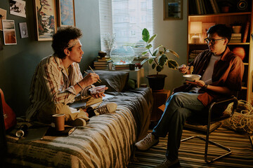 Biracial roomies eating Chinese instant noodles and chatting in their dorm room during dinner time