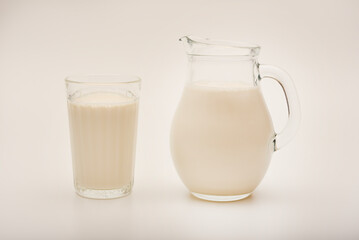 Melted milk in a milk jug and in a glass on a white background. Milk in a bowl.