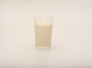 Melted milk in a glass on a white background. Milk in a bowl.