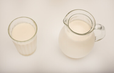 Melted milk in a milk jug and in a glass on a white background. Milk in a bowl.