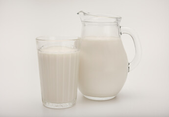 Melted milk in a milk jug and in a glass on a white background. Milk in a bowl.