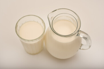 Melted milk in a milk jug and in a glass on a white background. Milk in a bowl.