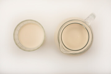 Melted milk in a milk jug and in a glass on a white background. Milk in a bowl.