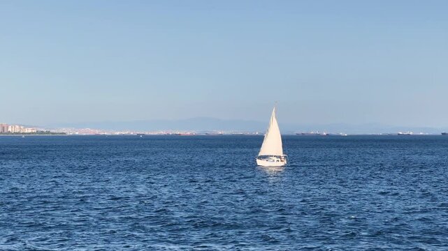 White sloop rigged yacht sailing in Marmara Sea at sunset. Sailing ship in full sail off the coast of Prince Islands of Istanbul City. Yachting at windy day. Sailing boat video. Sailboat
