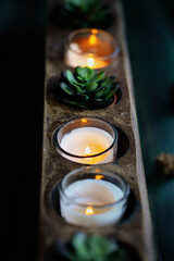 Antique wooden sugar mold used for autumn décor of burning candles and little succulent plant for a moody Thanksgiving table decoration. Selective focus with  blurred background. Top view. 