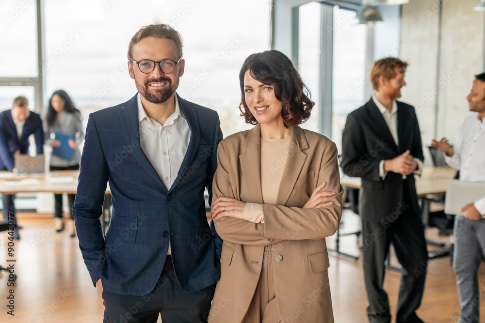 Fototapete a man and woman in business attire stand confidently in front of a large window. they are both smili