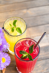 Colored summer lemonades with ice and mint on wooden table