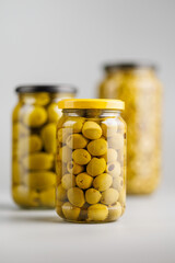 Pickled green olives in brine in jar on gray background.