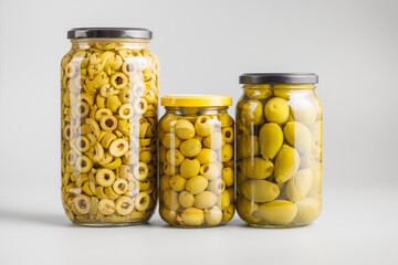 Pickled green olives in brine in jar on gray background.