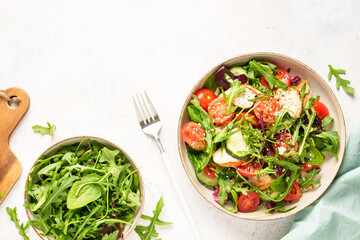 Healthy food. Green salad with baked chicken breast, fresh salad leaves and vegetables. Top view on white background.