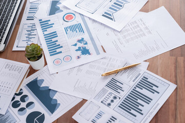 Obraz premium Piles of analyzed financial data dashboard on wooden office workspace desk. Business paper work with graph chart and analytic market trend indication data for strategic investment decision. Meticulous