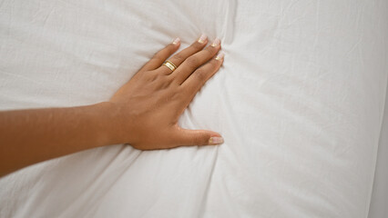 African american woman's hand with rings on white bedsheets