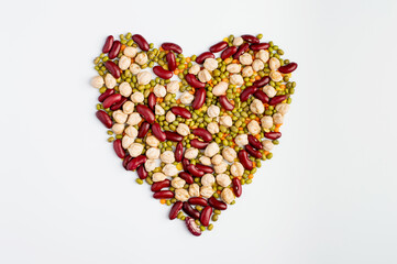 Assortment of bean mix in the shape of a heart on a light background. Lentils, mung beans, kidney beans and chickpeas top view. Vegetarian products.