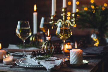 Rustic elegant table decor for christmas family dinner. Center piece with white candle, pine cone, fir tree branches. Zero waste eco-friendly home decoration. Cozy atmosphere, wooden background.