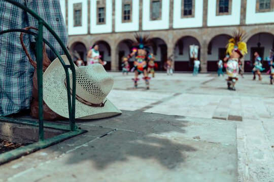 Sombrero en una banca y personas danzando 