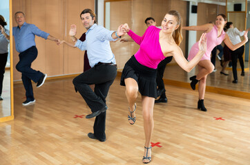 Active middle-aged pair practicing Latino dance in training hall during dancing-classes. Pairs...