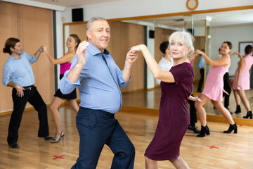 Fototapeta premium Couple of mature dancers rehearsing ballroom dances in dance studio