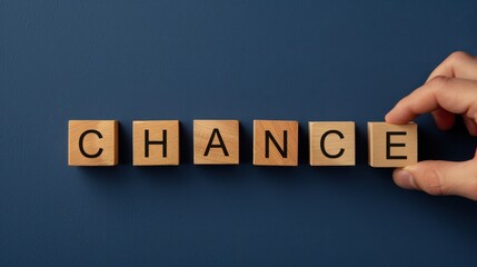 Hand pick the chance word wooden block on navy background for opportunity and motivation.