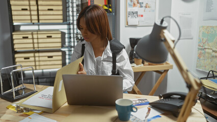 An african american woman detective working at her desk inside a police station office surrounded...