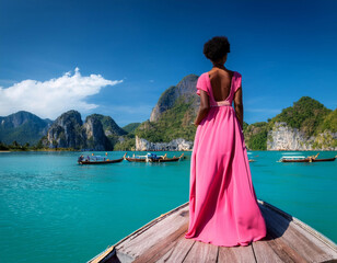 Femme d'origine africaine en robe rose sur une pirogue en Thaïlande