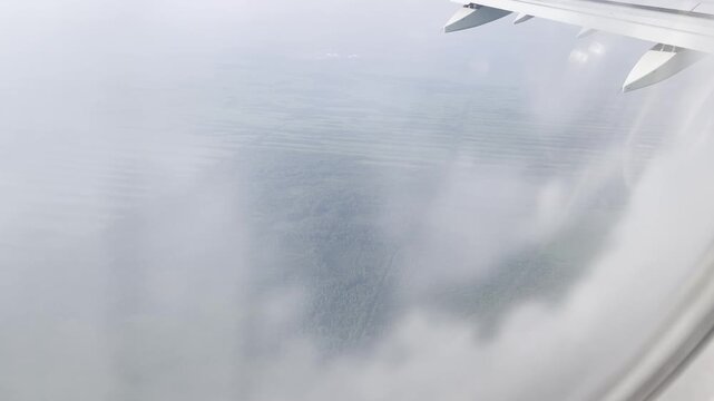 View of green agricultural fields through clouds in plne porthole in summer