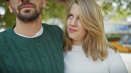 Obraz premium A loving couple sharing an intimate moment outdoors surrounded by greenery in a city park.
