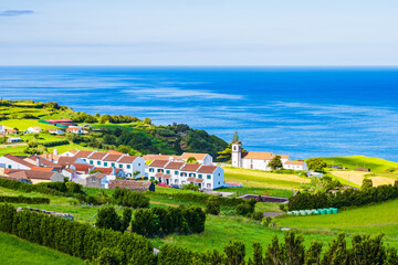 View of small town with typical houses and church on north eastern coast, Sao Miguel island, Azores, Portugal