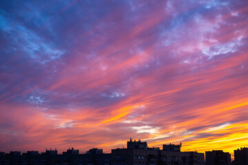 Obraz premium Sunset over city. Evening city landscape. Sunset over multi-story buildings. Cityline with colorful sky. Residential area of the city in evening. Cityscape with summer sunset. Town, metropolis