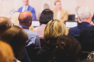 Audience at the modern conference hall listens to panel discussion, people on a congress together...