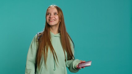 Jolly teenage woman holding passport, going on adventure trip, looking around. Cheerful wanderlust tourist backpacking, sightseeing, visiting attractions, isolated over studio backdrop, camera A