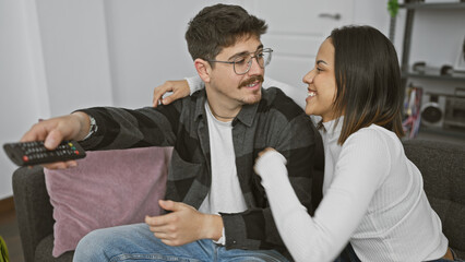 Happy couple enjoying a cozy moment together on the sofa in a modern living room, man holding remote.