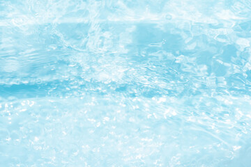 Blue water with ripples on the surface. Defocus blurred transparent blue colored clear calm water surface texture with splashes and bubbles. Water waves with shining pattern texture background.