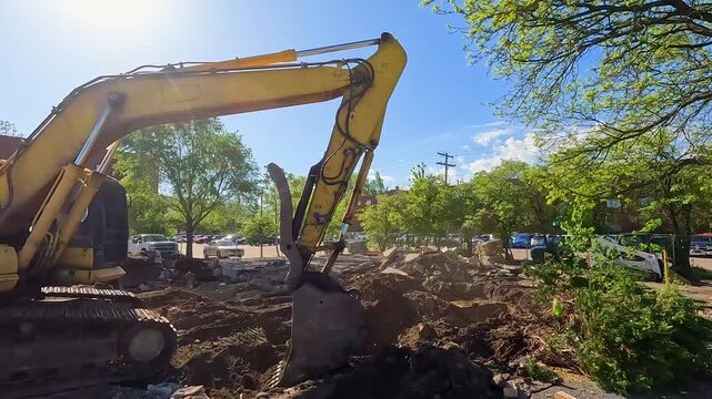 Construction Equipment Excavator Digging in the Dirt. Excavation vehicle uses an industrial scoop to dig into the soil. Sunlight shines upon the scene with dirt and dust permeating the air.