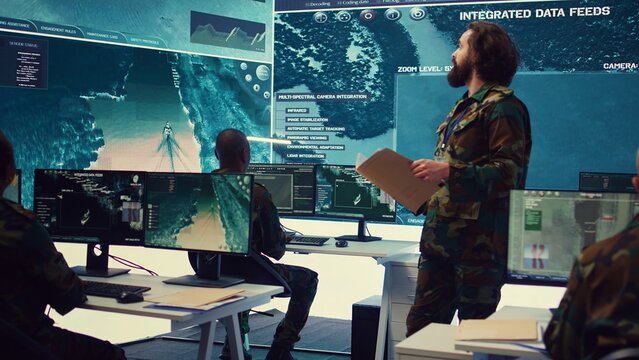 Army major reads operation details from a case file in a control center military headquarters, manages personnel and resources for logistical or operational missions. Task force command. Camera B.