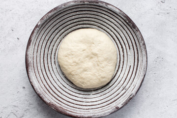 Overhead view of bread dough rising in banneton basket , top view of proofing dough in a wood proofing basket, process of making artisan bread