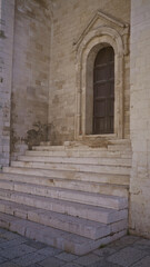 Ancient stone staircase leading to an ornate wooden door in bari, italy, showcasing historical architecture in a european outdoor setting.