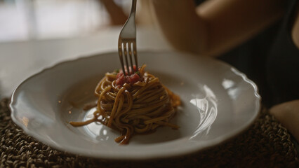 A woman enjoys a plate of spaghetti in an italian restaurant, highlighting the delicious pasta with tomato sauce for an authentic italy dining experience indoors.