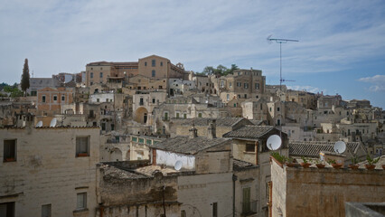 Panoramic view of the historic town of matera in basilicata, italy, showcasing the densely built stone houses under a blue sky.