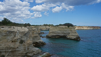 Scenic coastal cliffs under a partly cloudy sky at torre dell'orso in salento, puglia, italy, showcasing breathtaking rock formations and the turquoise adriatic sea.